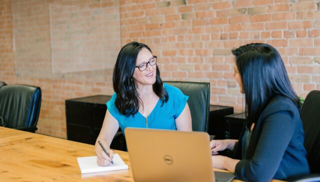 Two women inside office laughing together