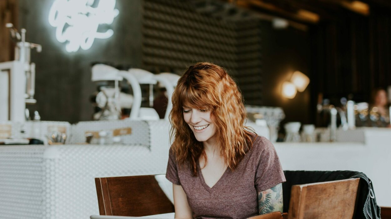 Happy lady at a coffee shop freelancing on her laptop