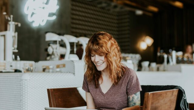 Happy lady at a coffee shop freelancing on her laptop