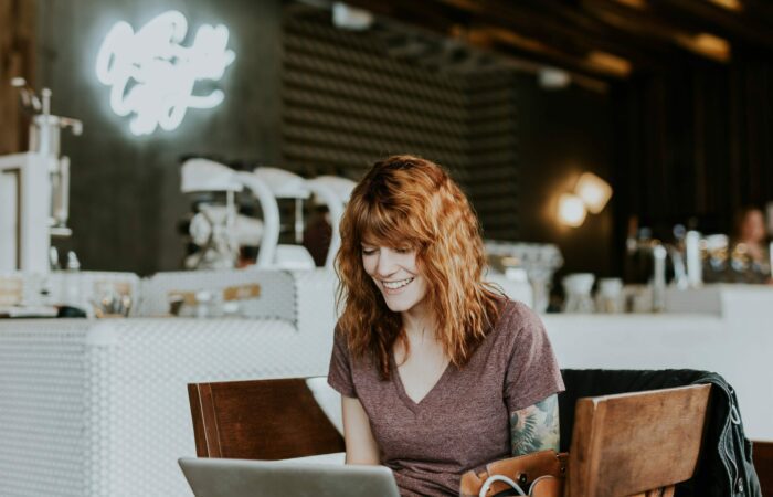 Happy lady at a coffee shop freelancing on her laptop