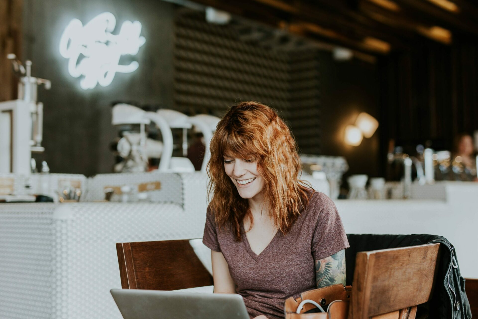 Happy lady at a coffee shop freelancing on her laptop