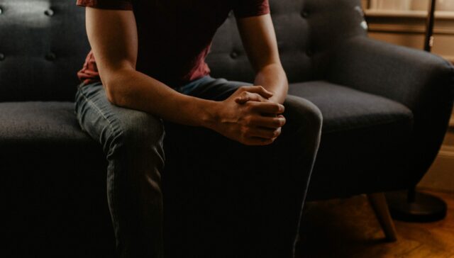 Young man sitting on a couch with his hands locked