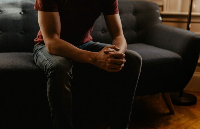 Young man sitting on a couch with his hands locked