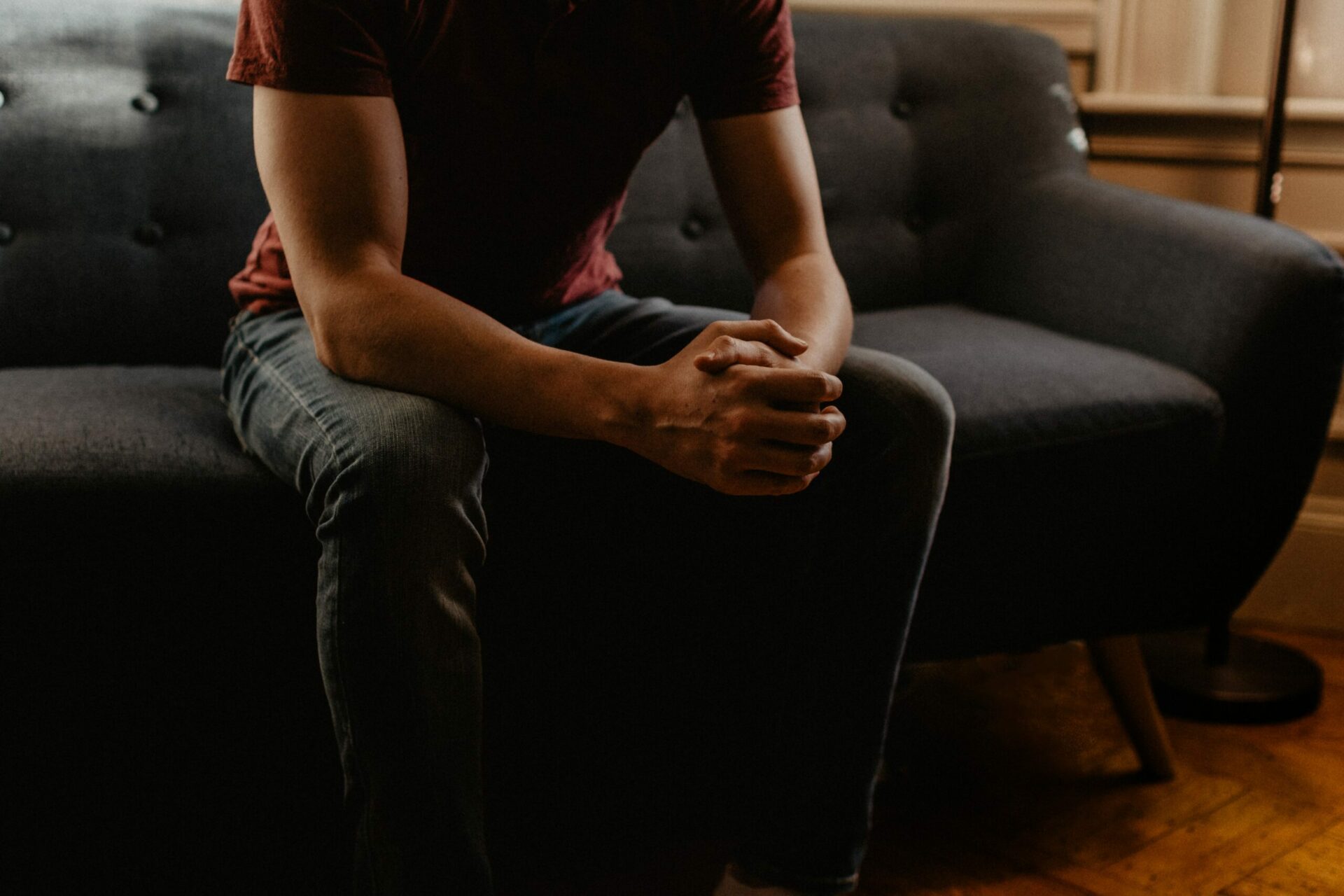 Young man sitting on a couch with his hands locked