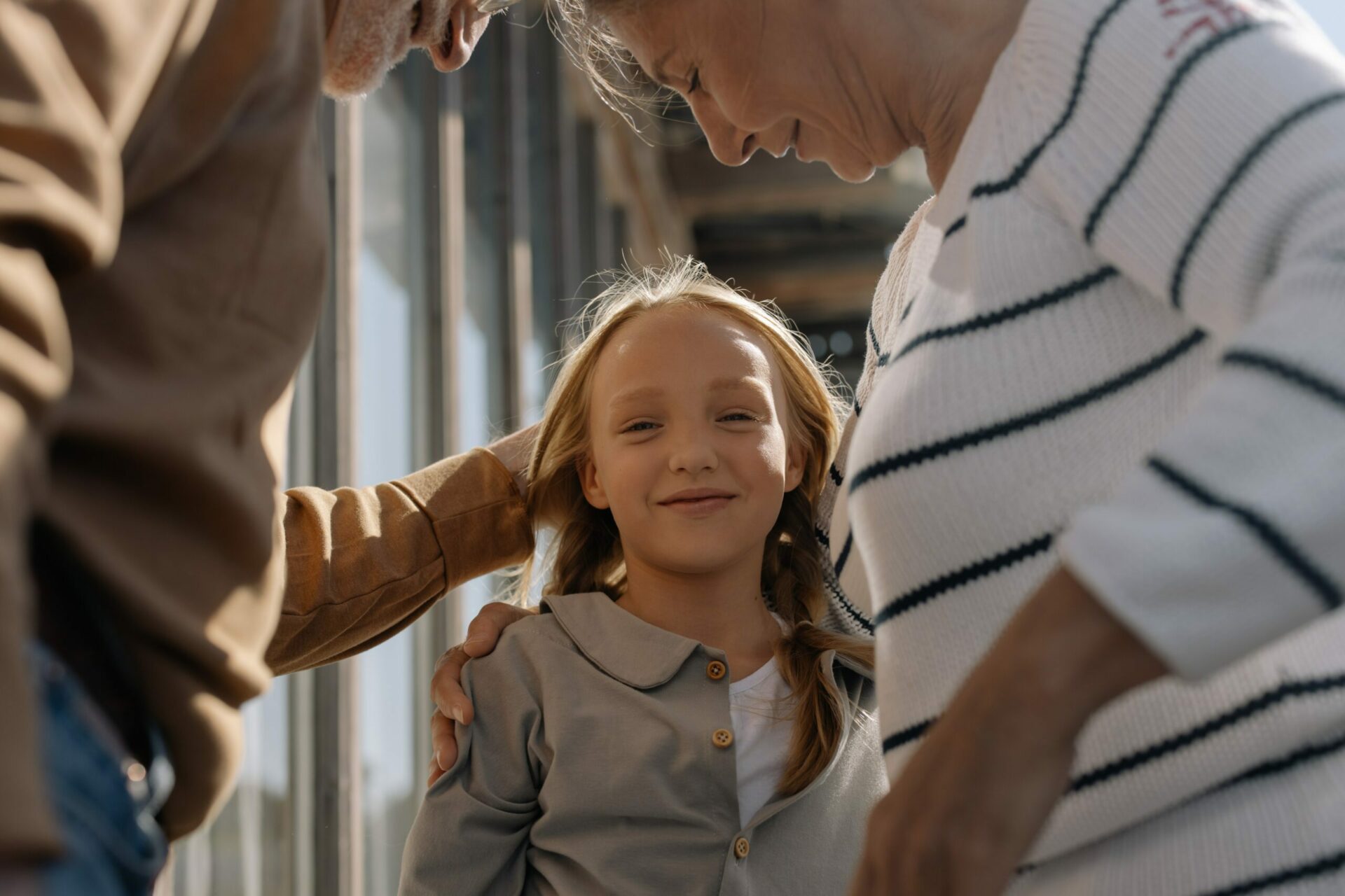 Two grandparents are holding their granddaughter that is smiling at the camera