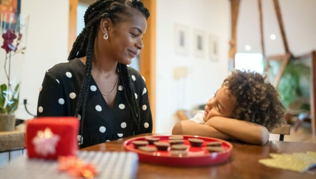 Mother and son looking at each other inside their house at a table