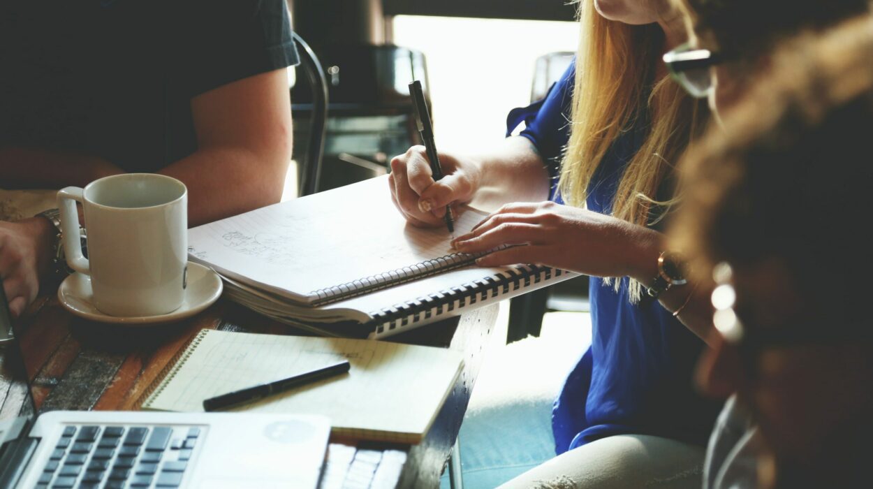 Four business people sitting at a table and one woman is writing notes on her notepad