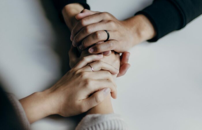 Close up of two people having a conversation and holding hands in support