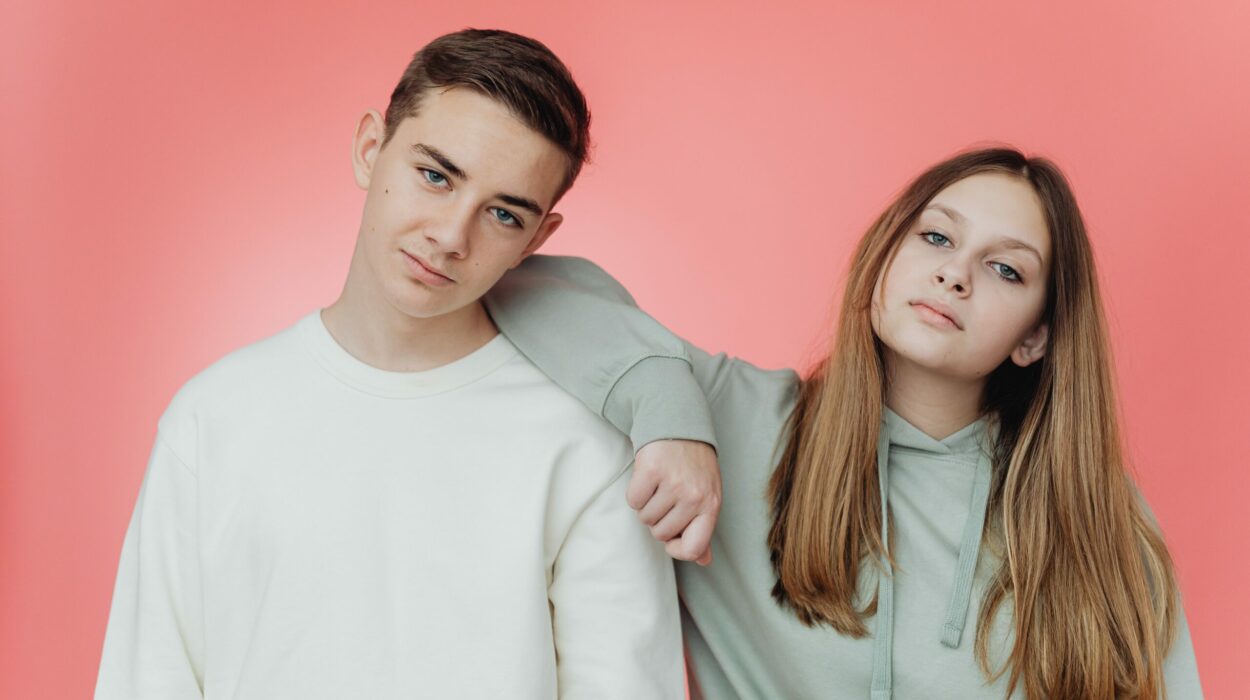 Two young people posing against a pink background.