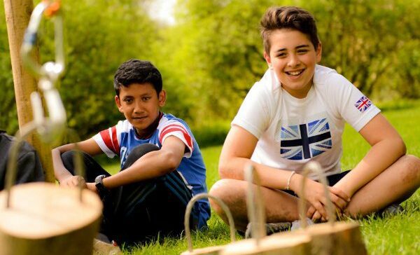 Two boys sitting on the grass looking at the camera