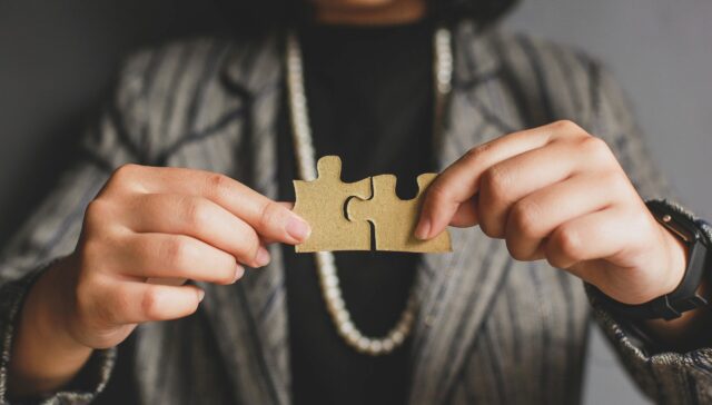 A woman holding two jigsaw puzzle pieces together