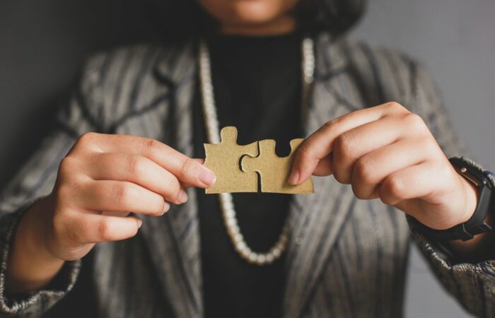 A woman holding two jigsaw puzzle pieces together