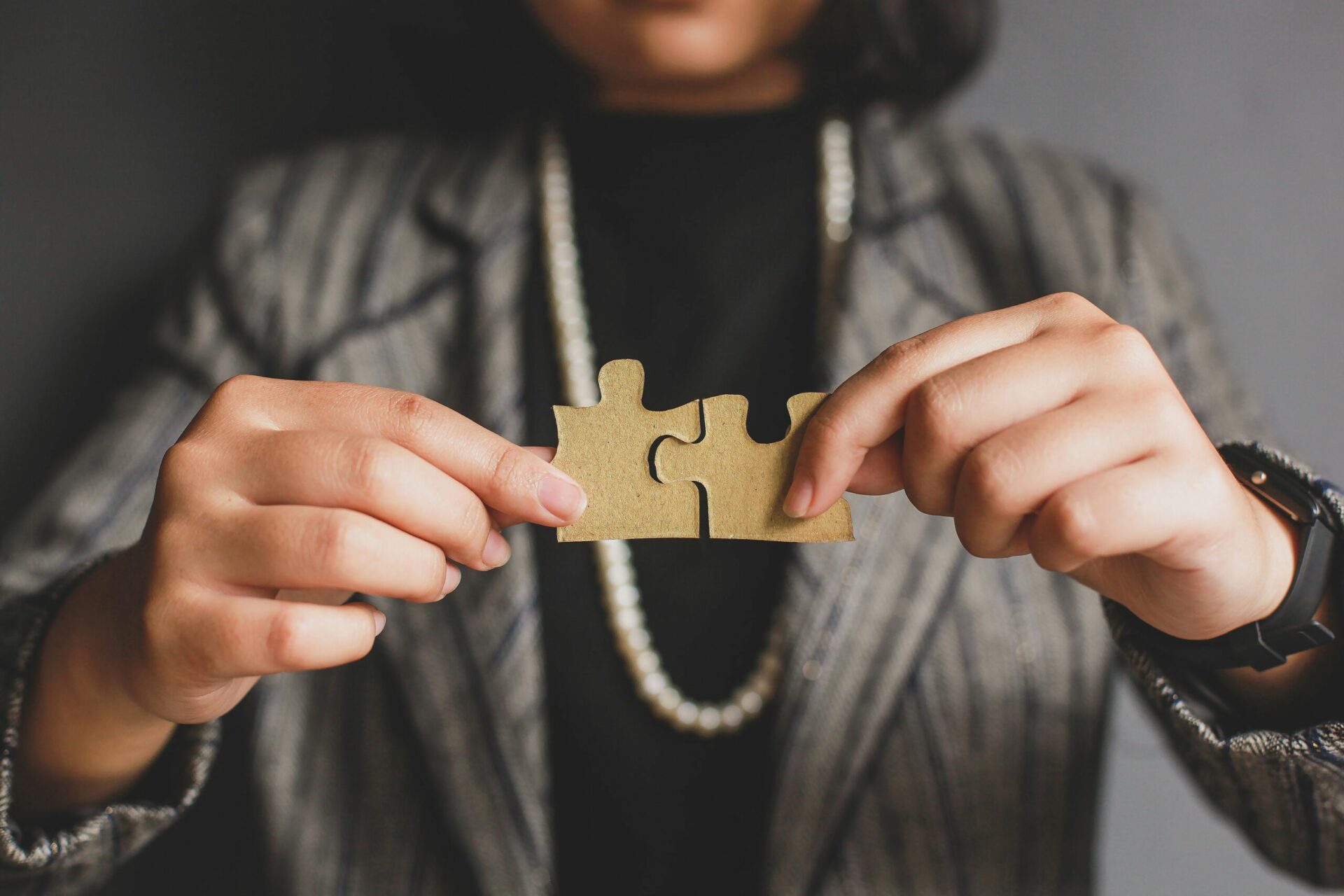 A woman holding two jigsaw puzzle pieces together