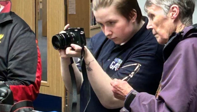 Aaron Bell showing someone how to use a camera.