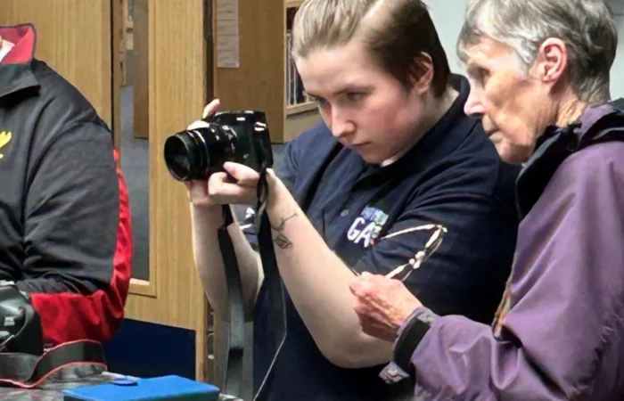 Aaron Bell showing someone how to use a camera.