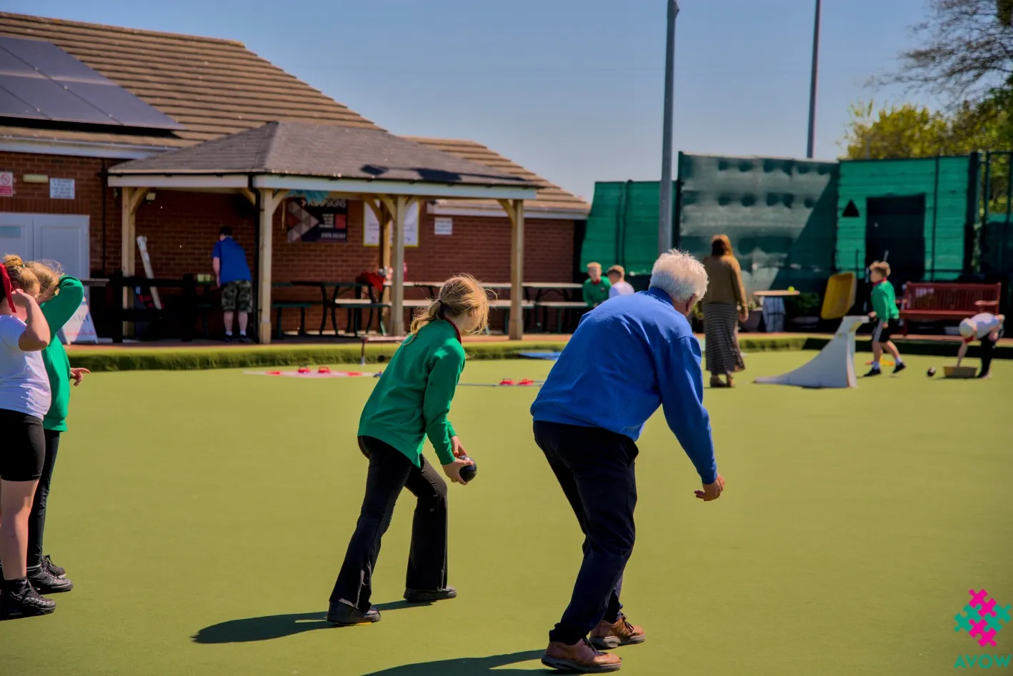 Intergenerational Week - Old Man teaching young girl to bowl.